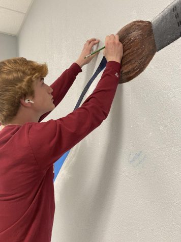 Christian Bollman paints the mural in the art hallway.